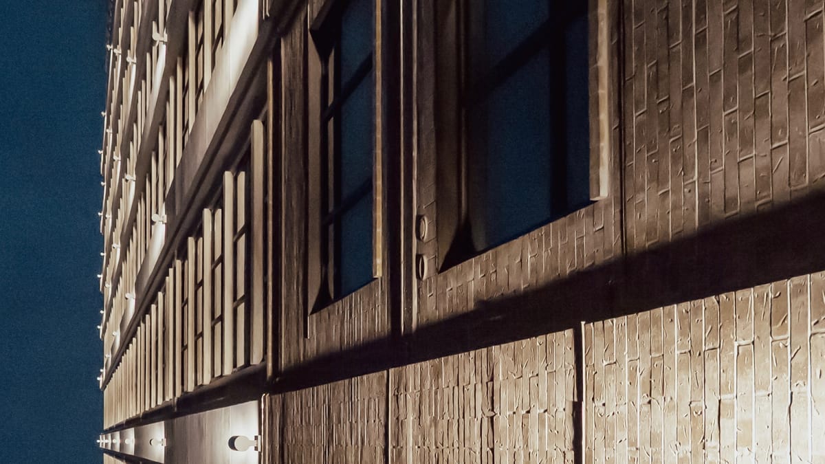 Nighttime view of a downtown Nashville high-rise, photographed from below, highlighting its height and brick facade.