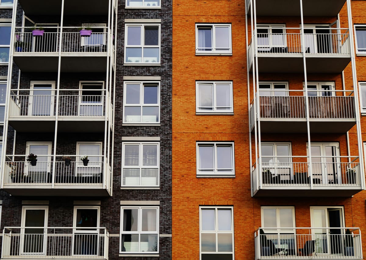 Apartment exterior showing windows and balconies. Photo by George Becker: https://www.pexels.com/photo/photography-of-orange-and-gray-building-129494/